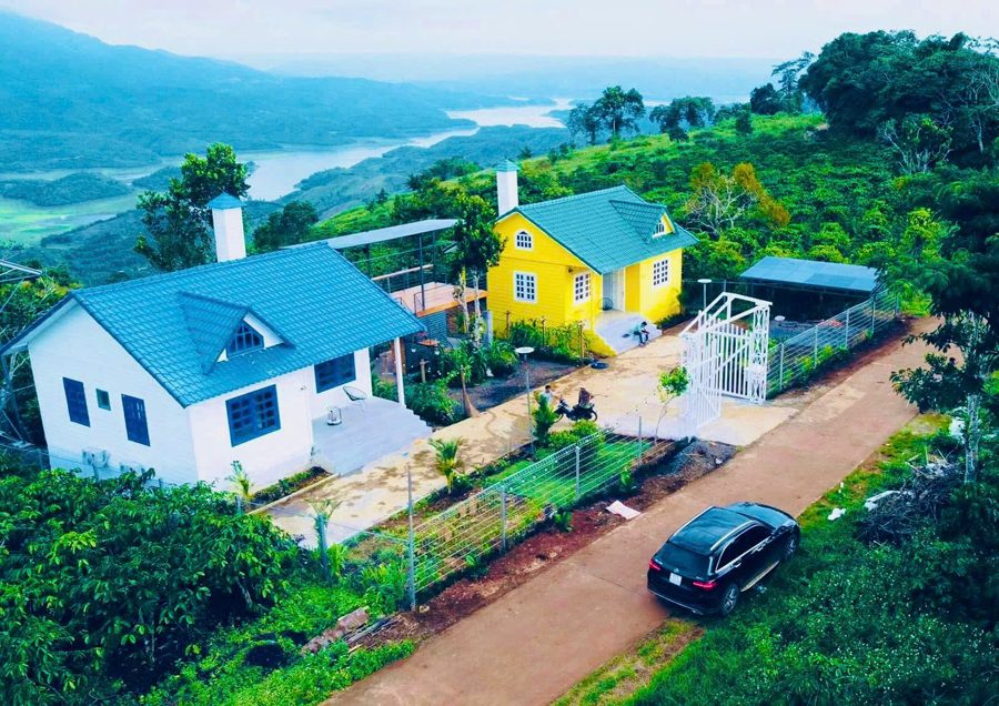 Hai nhà vàng và trắng giữa vườn, phía xa là hồ Tà Đùng
