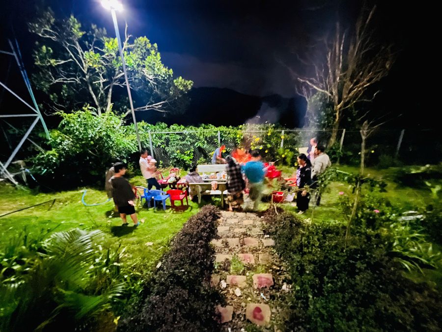 Nhóm khách quây quần trong vườn farmstay buổi tối